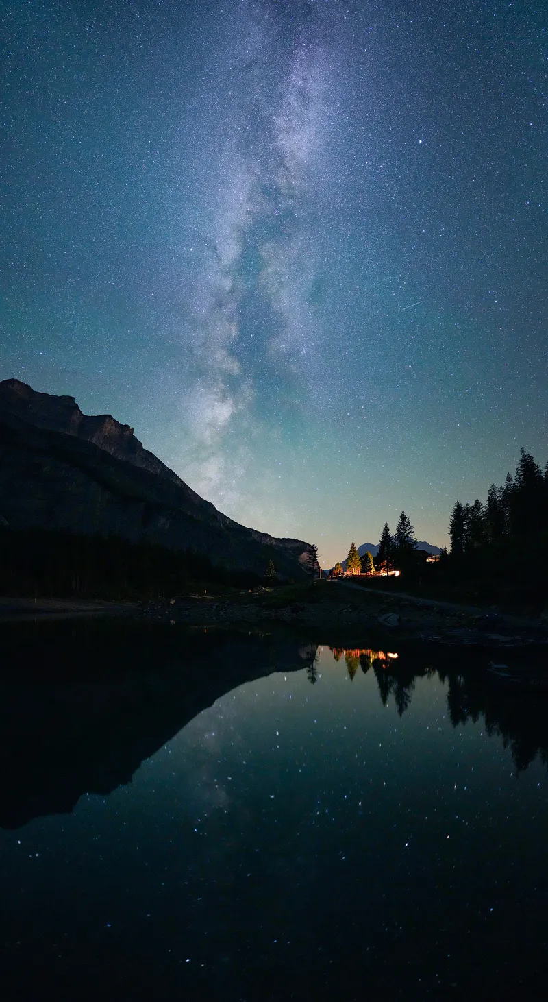 The Milky Way reflected in a mountain lake far from city lights, in Switzerland.