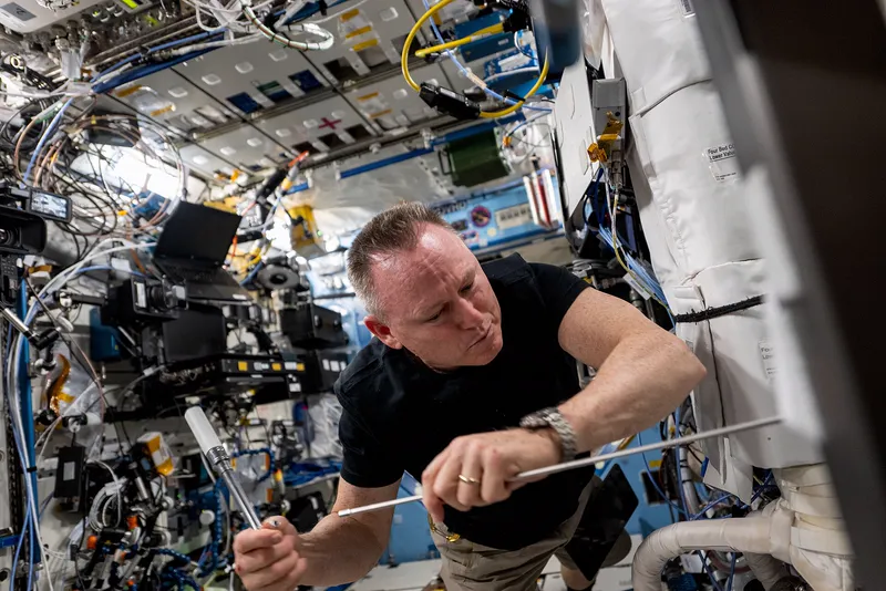 Inside the Destiny laboratory on the space station, packed with equipment racks.