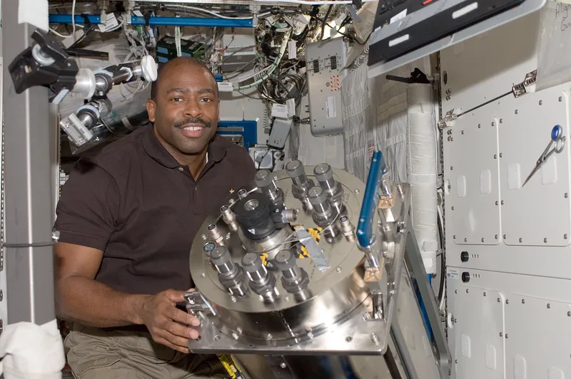 An astronaut holding a part of the space station's water recycling system that had to be replaced.