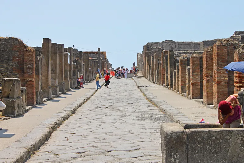 Via dell'Abbondanza, one of Pompeii's main streets, with a fountain basin at the roadside.
